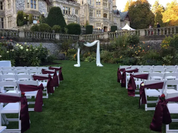 A wedding ceremony in the grass with white chairs.