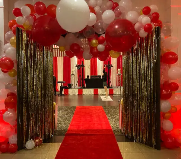 A red carpet and balloons in the middle of a room.