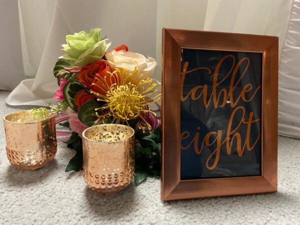 A table with flowers and candles next to a sign.