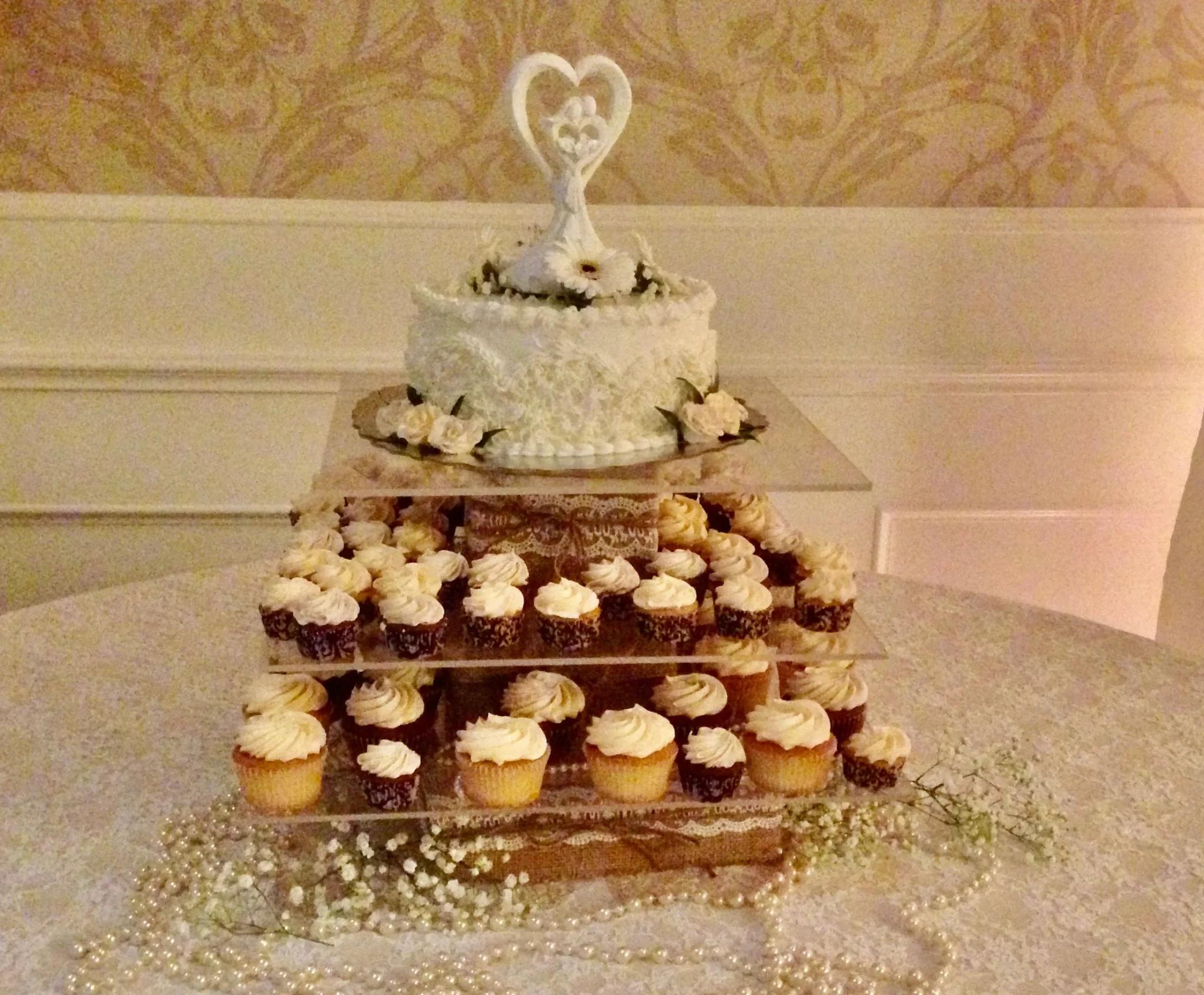 A wedding cake and cupcakes on display.