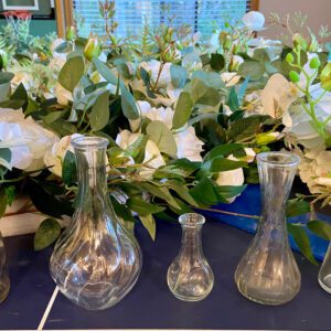 A table with several vases and flowers on it.