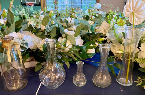 A table with several vases and flowers on it.