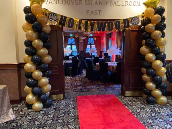 A red carpet and balloons in the middle of an entrance way.