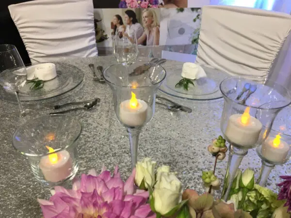 A table set with candles and flowers on top of it.