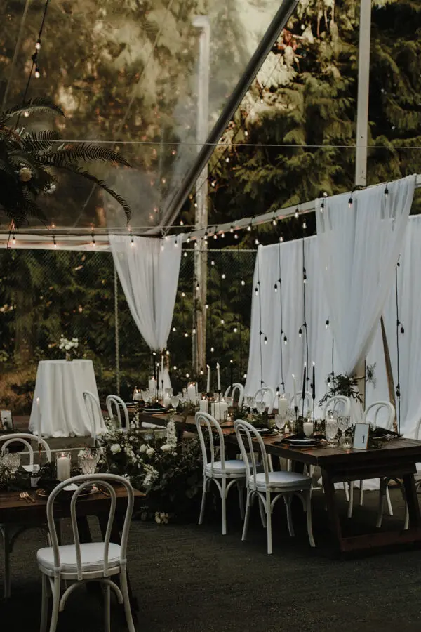 A table set up with white chairs and lights.