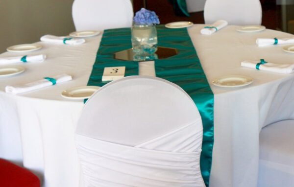 A table with white chairs and green satin runner.