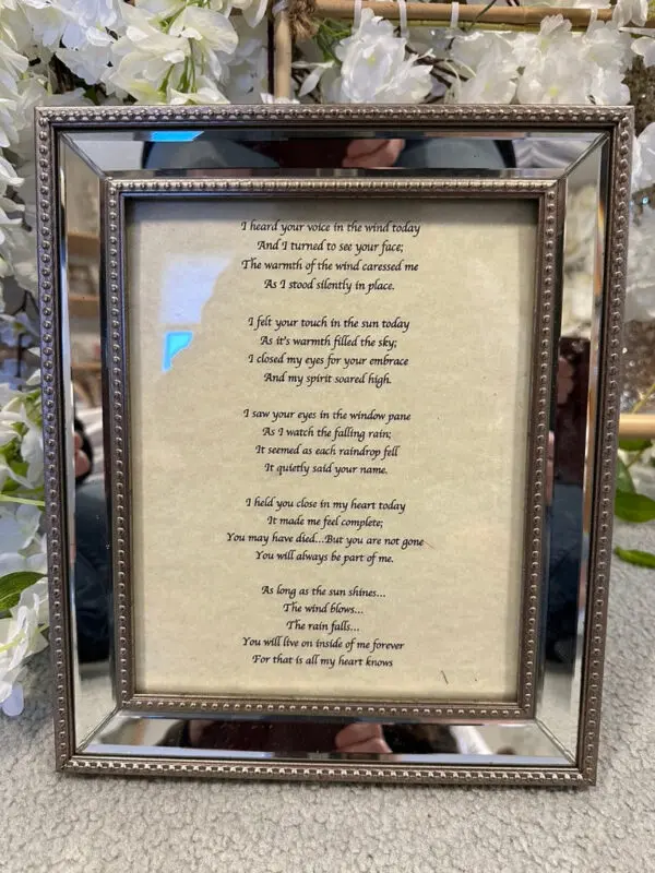 A framed poem is displayed in front of a mirror.