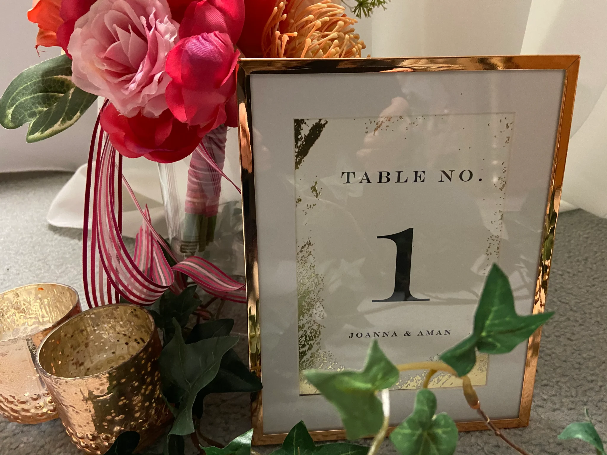 A table number with flowers and ivy in the background.