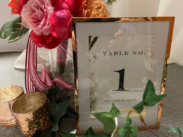 A table number with flowers and greenery in it.