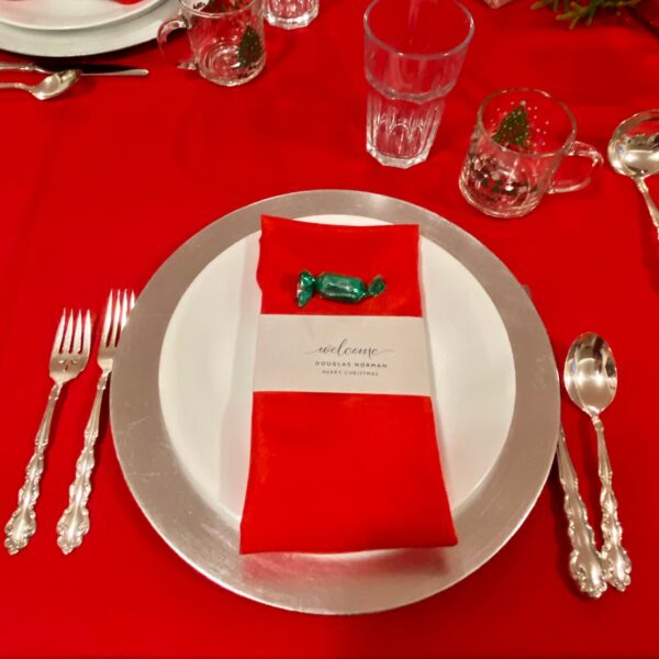 A red table cloth with silverware and plates on it.