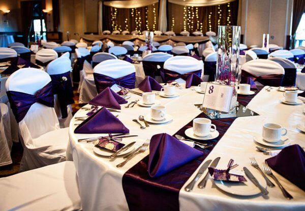 A banquet hall with tables and chairs set up for a wedding.