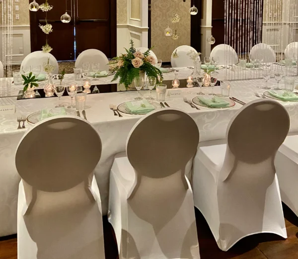 A long table with white chairs and plates on it