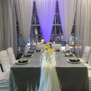 A table set up with white chairs and yellow flowers.