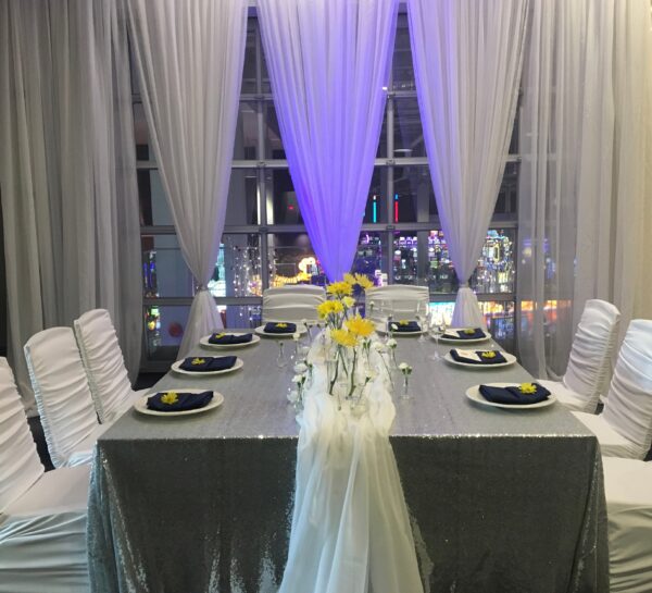 A table set up with white chairs and yellow flowers.