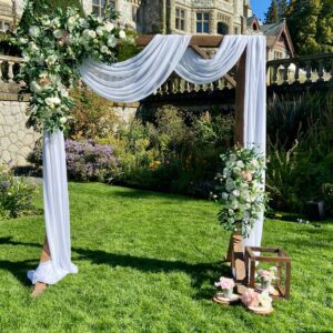 A wedding arch with white flowers and greenery.