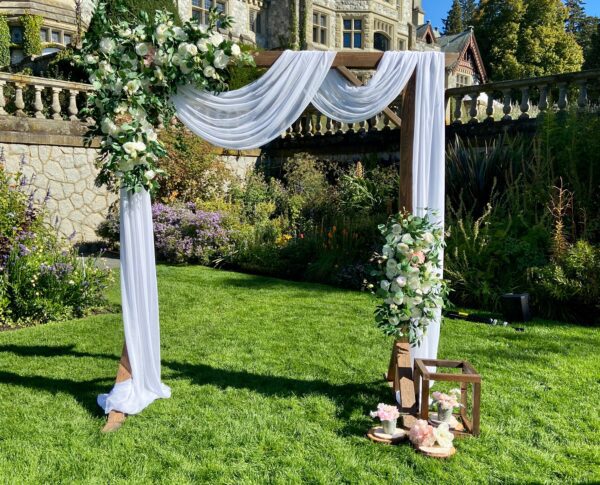 A wedding arch with white flowers and greenery.