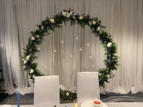 A wedding arch with white flowers and greenery.