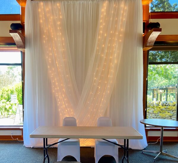 A white table with two chairs and lights on the wall.