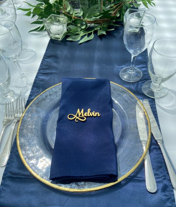 A blue table cloth with a glass plate and silverware.