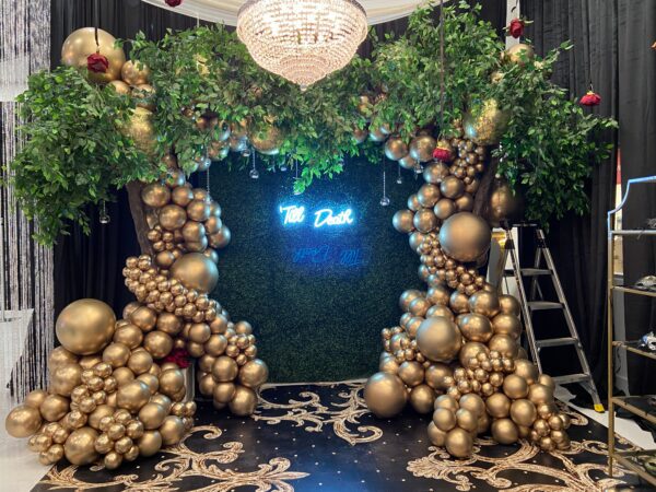 A room with gold balloons and greenery