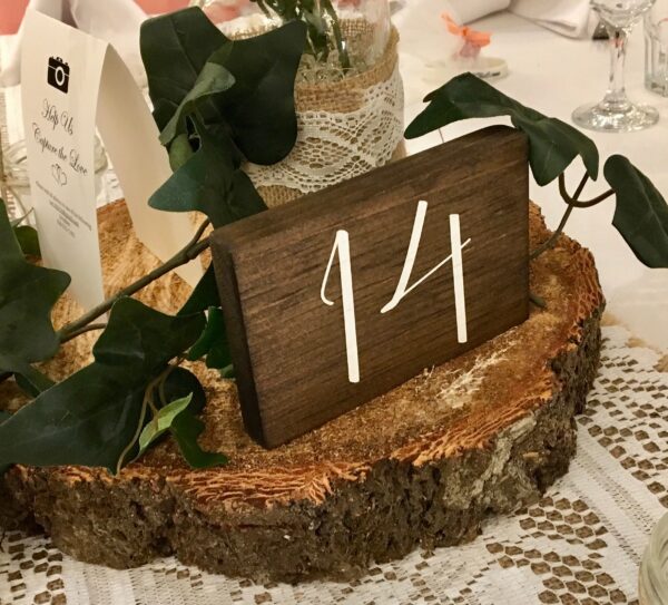 A wooden table number with white numbers on it.