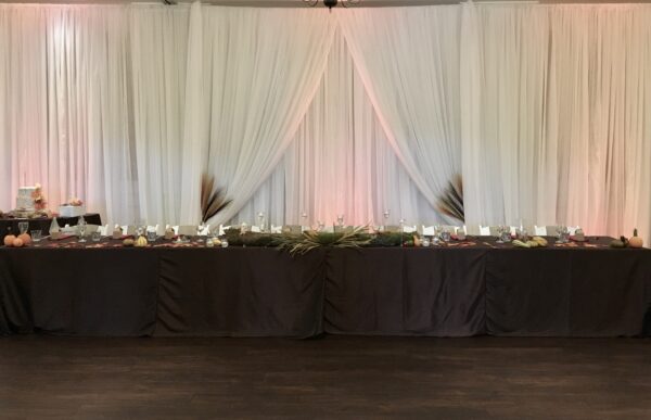 A table with candles and flowers in front of a white curtain.