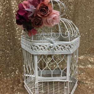 A white bird cage with flowers in it.