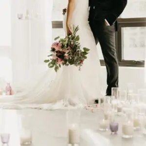 A bride and groom standing in front of candles.