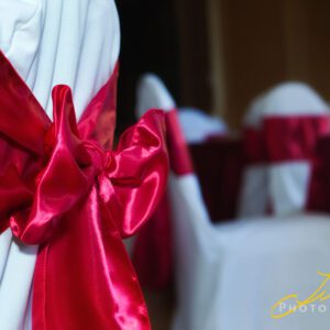 A close up of some red bows on white chairs