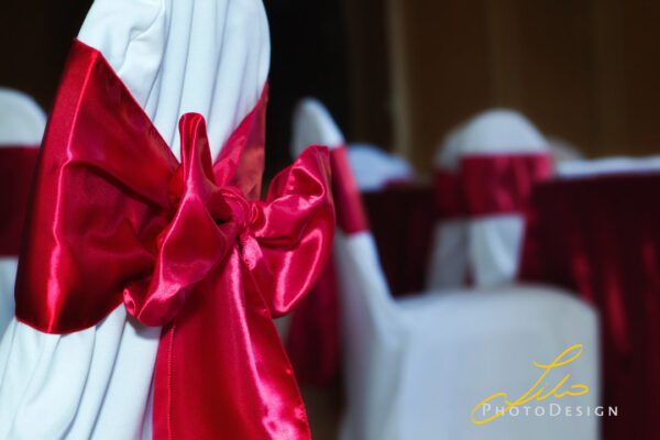 A close up of some red bows on white chairs