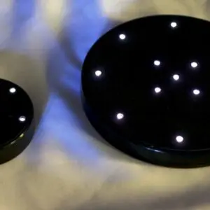 Two black discs with white lights on top of a bed.