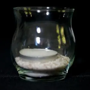 A candle in a glass bowl with sand inside.