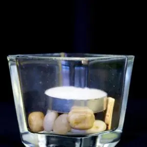 A candle in a glass with rocks inside of it.