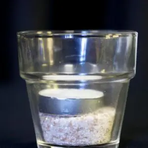 A glass cup with sand inside of it