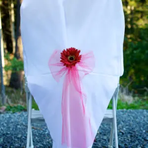 A chair with a pink bow and flower on it.