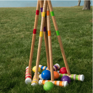 A group of croquet balls and sticks in the grass.