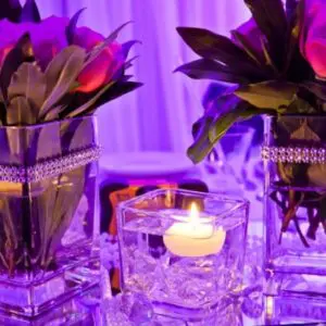 A candle lit in a glass vase with flowers.