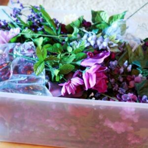 A container of flowers and leaves in it.