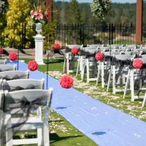 A wedding ceremony with white chairs and blue carpet.