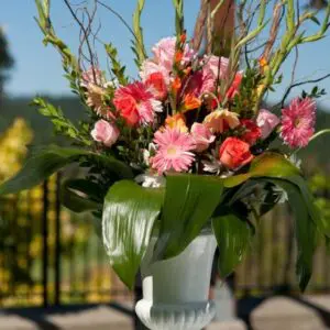 A vase of flowers on the ground outside