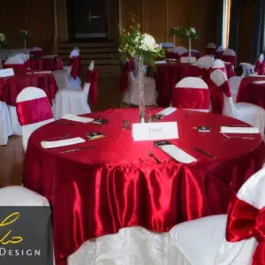 A room with many tables and chairs covered in red cloth.