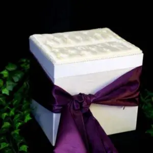 A white box with purple ribbon on top of it.