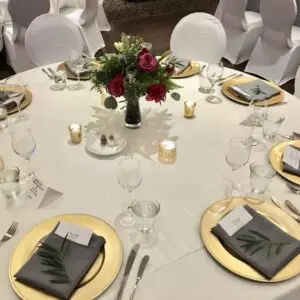 A table set with plates and silverware, candles, and flowers.