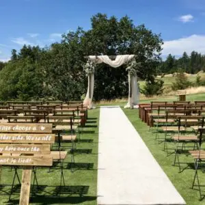 A wedding ceremony with benches and an arch.