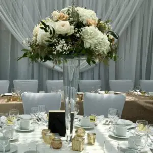 A table set up with white and beige flowers.