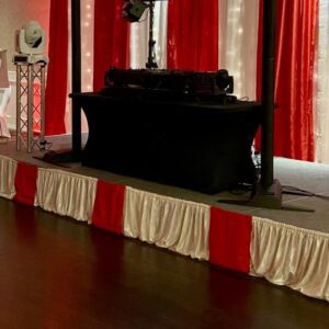 A stage with red and white curtains in the background.