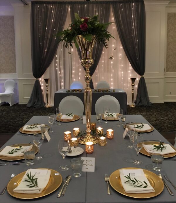 A table set with plates and candles in front of a curtain.