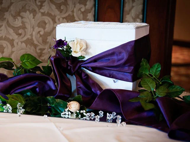 A white box with purple ribbon on top of it.