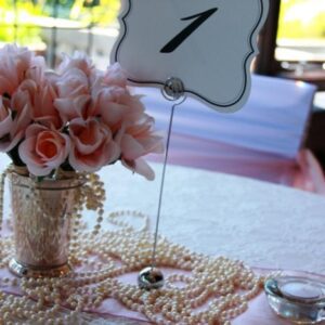 A table with a number 1 sign and pink flowers in a vase.