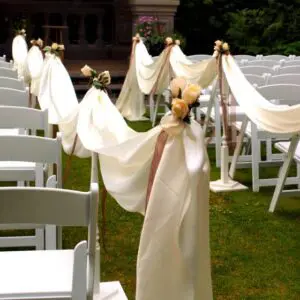 A row of white chairs with white cloth draped over them.